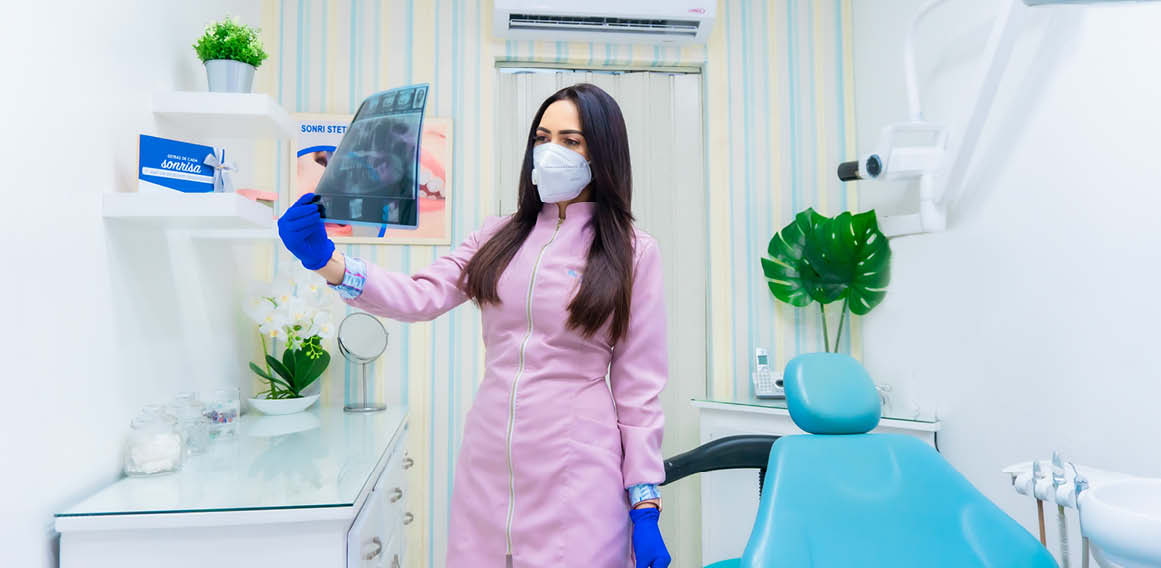 Profesional revisa rayos x de paciente en clínica dental.