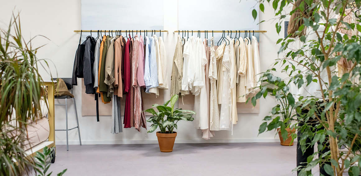 Burro de ropa en una tienda con plantas, mesa y silla