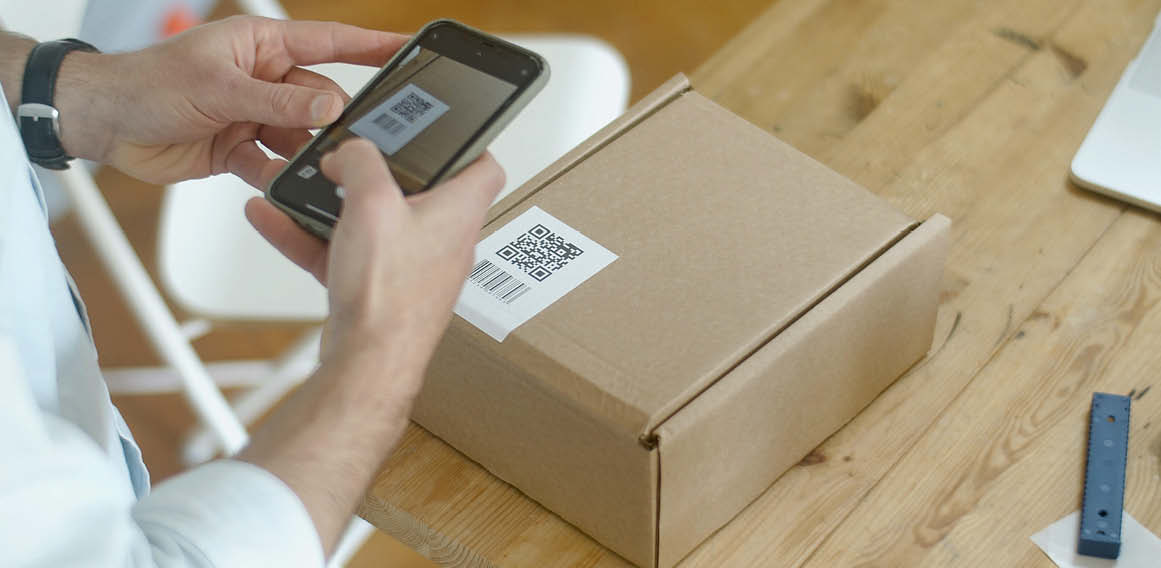 Código QR en un paquete y persona con teléfono móvil