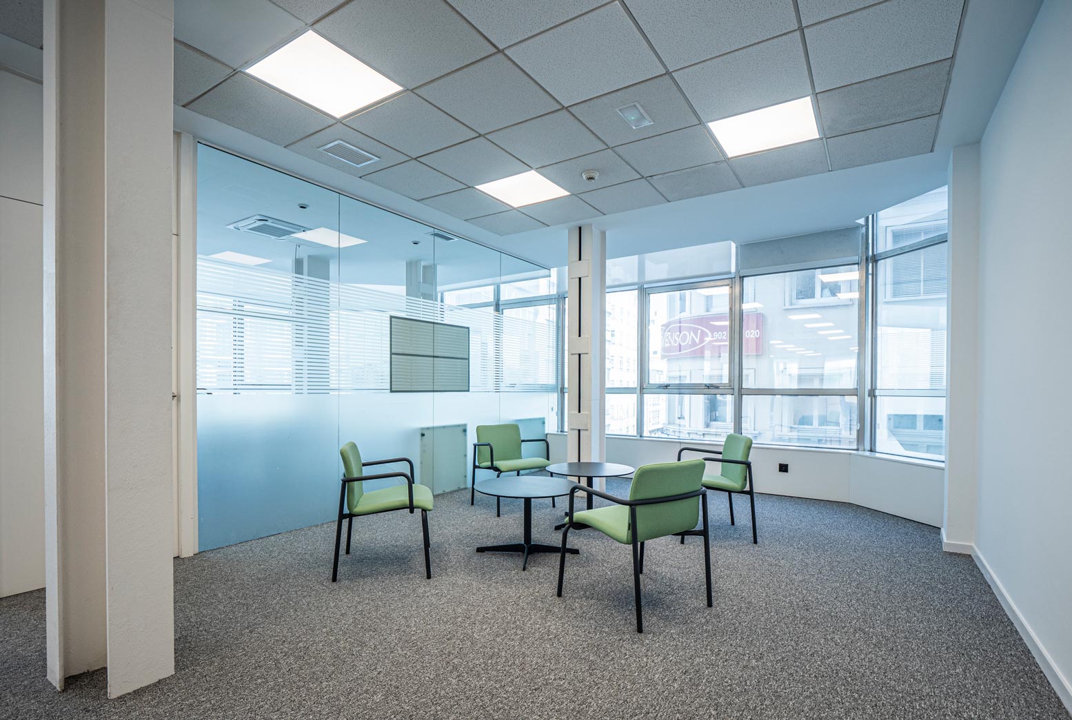 Mampara de vidrio en zona de espera de oficina y espacio de trabajo con mobiliario estándar y a medida
