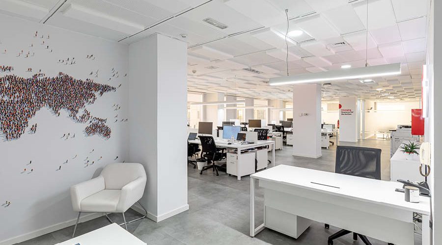 Zona de oficina con puestos operativos, mesa de recepcion, iluminacion natural y artificial, diseño de oficina
