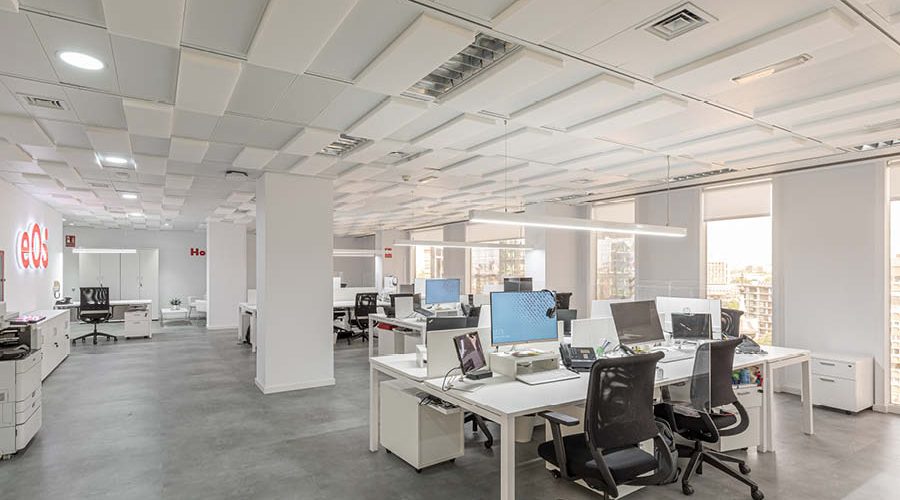 Puestos operativos en oficina con rotulo iluminado, sillas y mesas de trabajo, paneles fonoabsorbentes