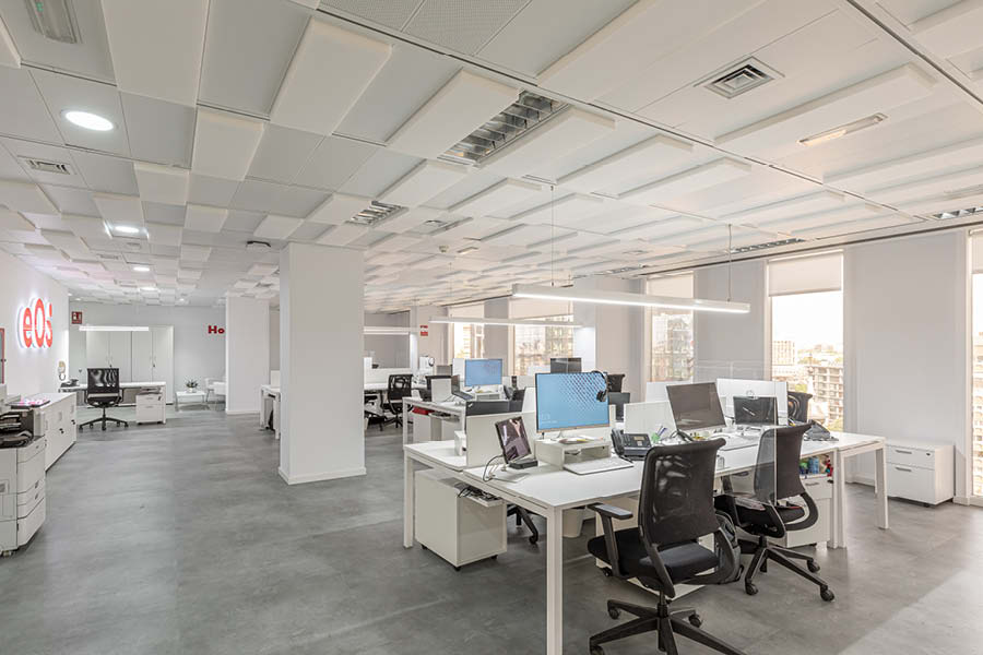 Puestos operativos en oficina con rotulo iluminado, sillas y mesas de trabajo, paneles fonoabsorbentes