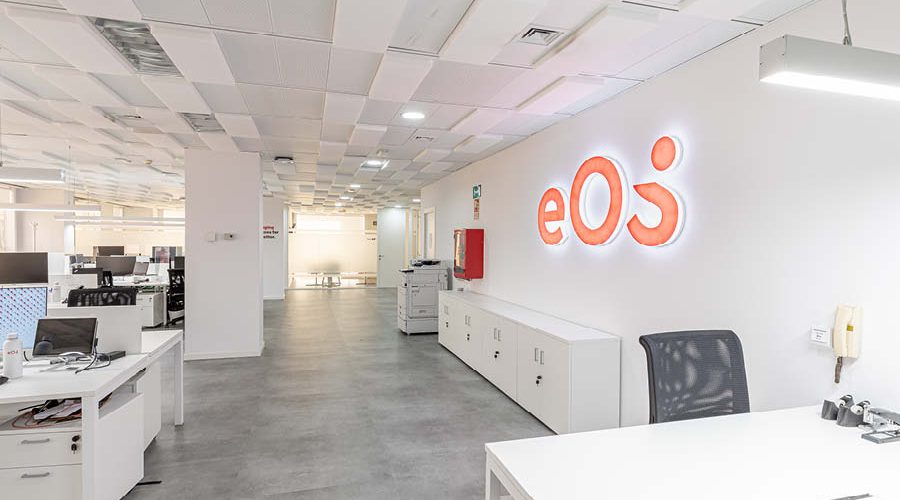 Rotulo iluminado con trabajos de branding, imagen nueva, en oficina con puestos operativos