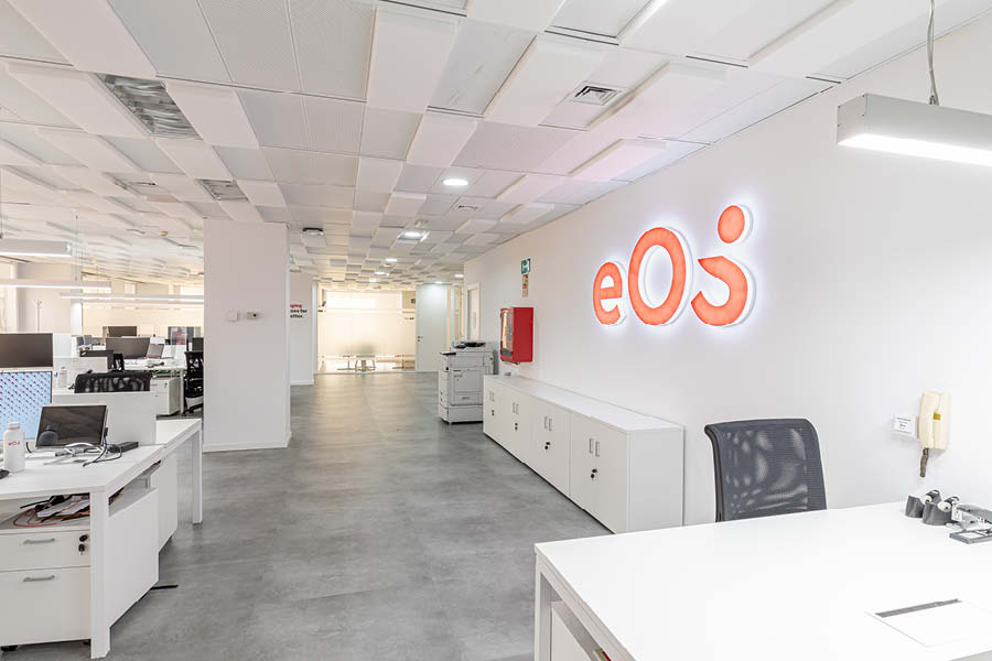 Rotulo iluminado con trabajos de branding, imagen nueva, en oficina con puestos operativos