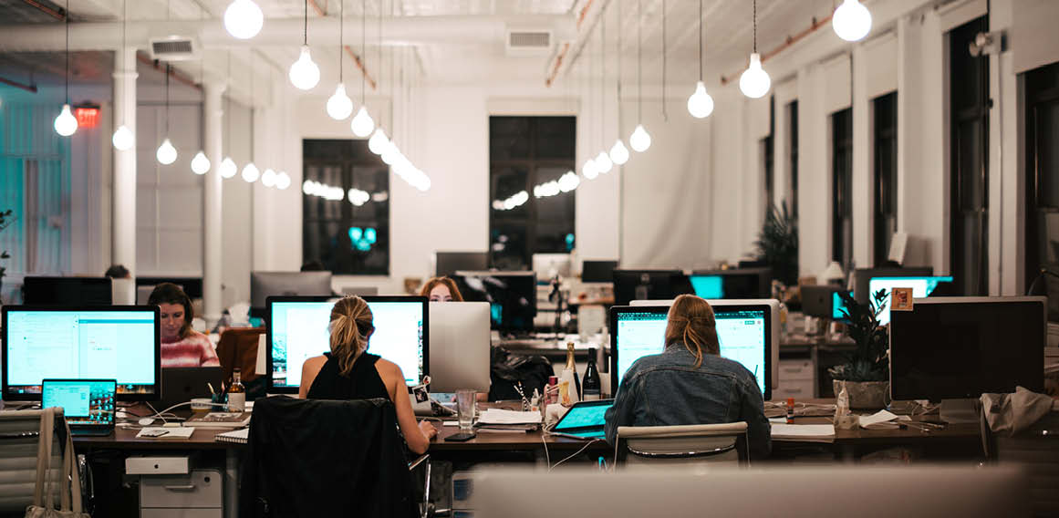 Unsplash oficina con personas trabajando con ordenadores e iluminación en mesas bench