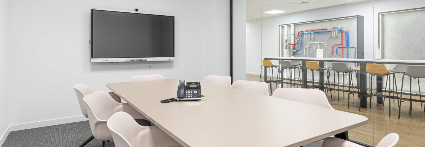 Sala de reuniones con monitor de TV y mesa de gran formato para espacio compartido de oficina