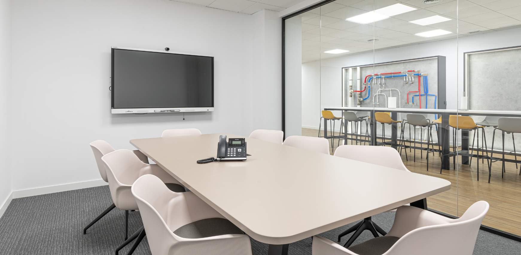 Sala de reuniones con monitor de TV y mesa de gran formato para espacio compartido de oficina