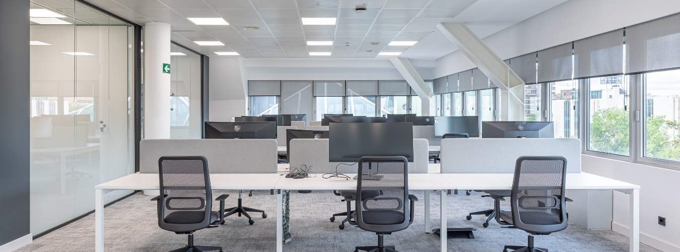 Sillas y mesas de puestos operativos en zona de oficina en Madrid