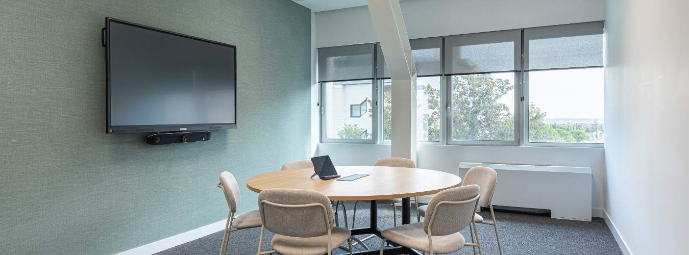 Sala de reuniones con mobiliario corporativo y pantallas tecnología