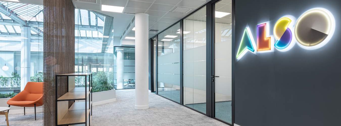 Rótulo corporativo en oficina en Madrid, zona de recepción con moqueta y mamparas