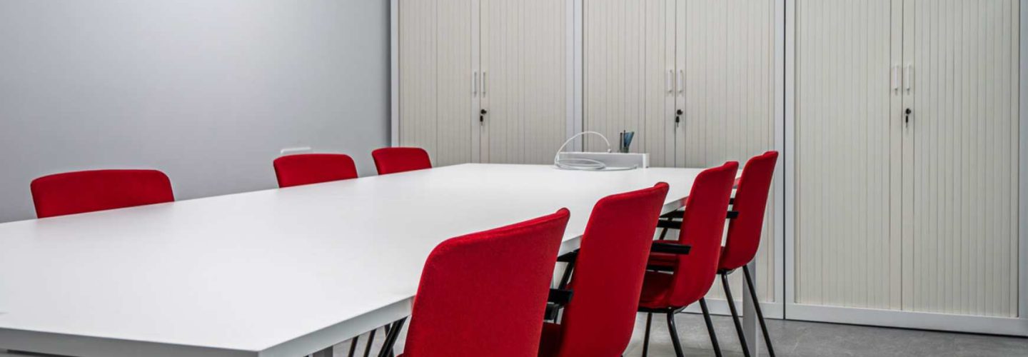 Sala de reuniones con mesa, armarios de almacenaje y sillas en oficina moderna
