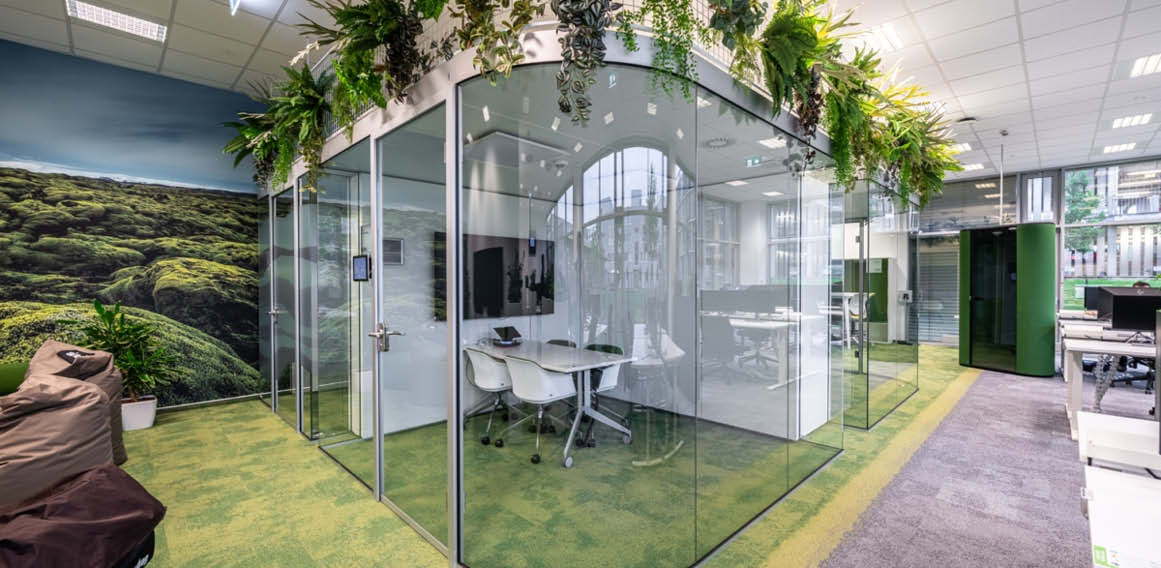 Oficina con vegetación y mamparas de vidrio en oficina open space
