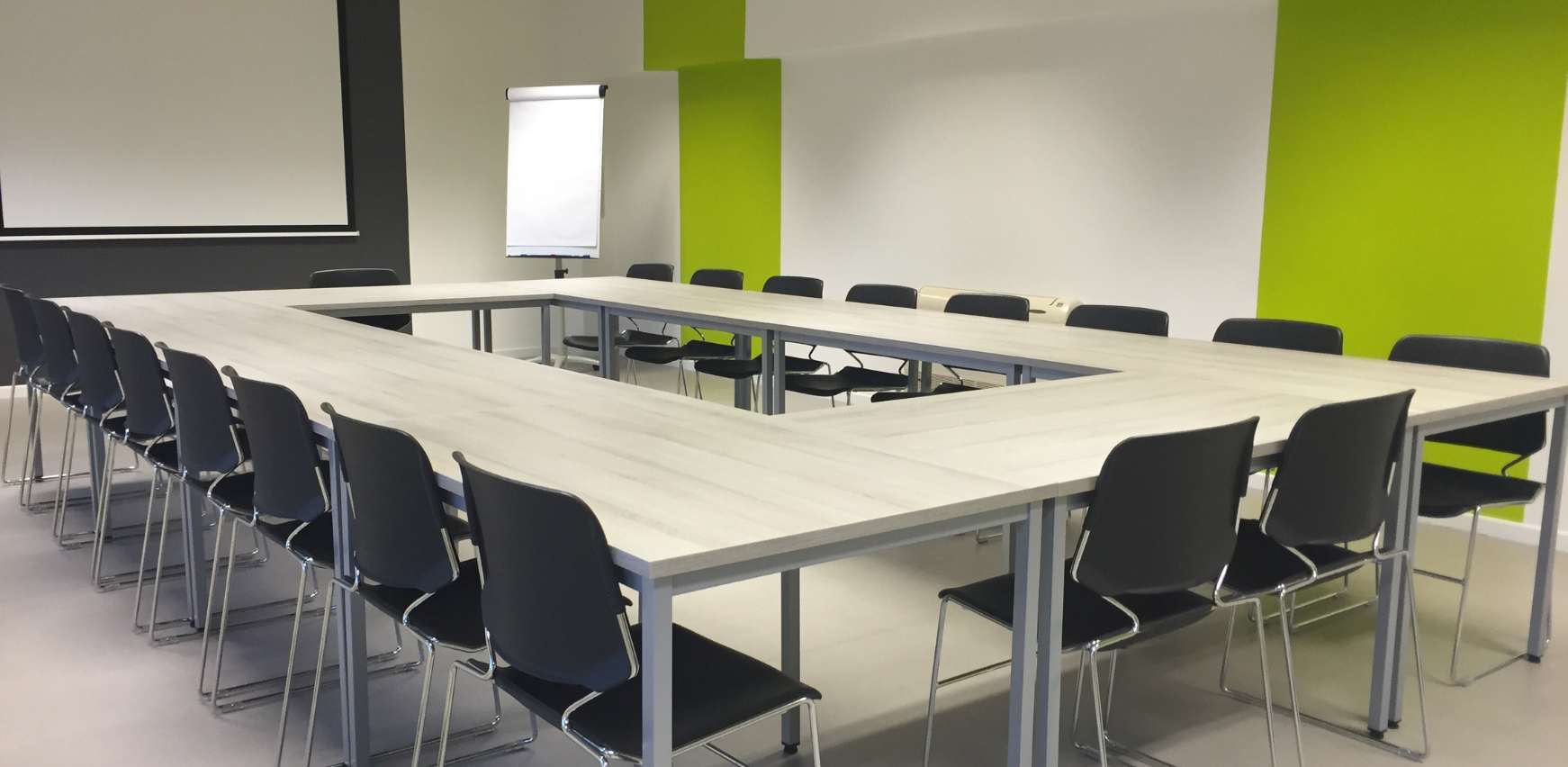Sala de reuniones y formaciones en forma de L con mobiliario operativo