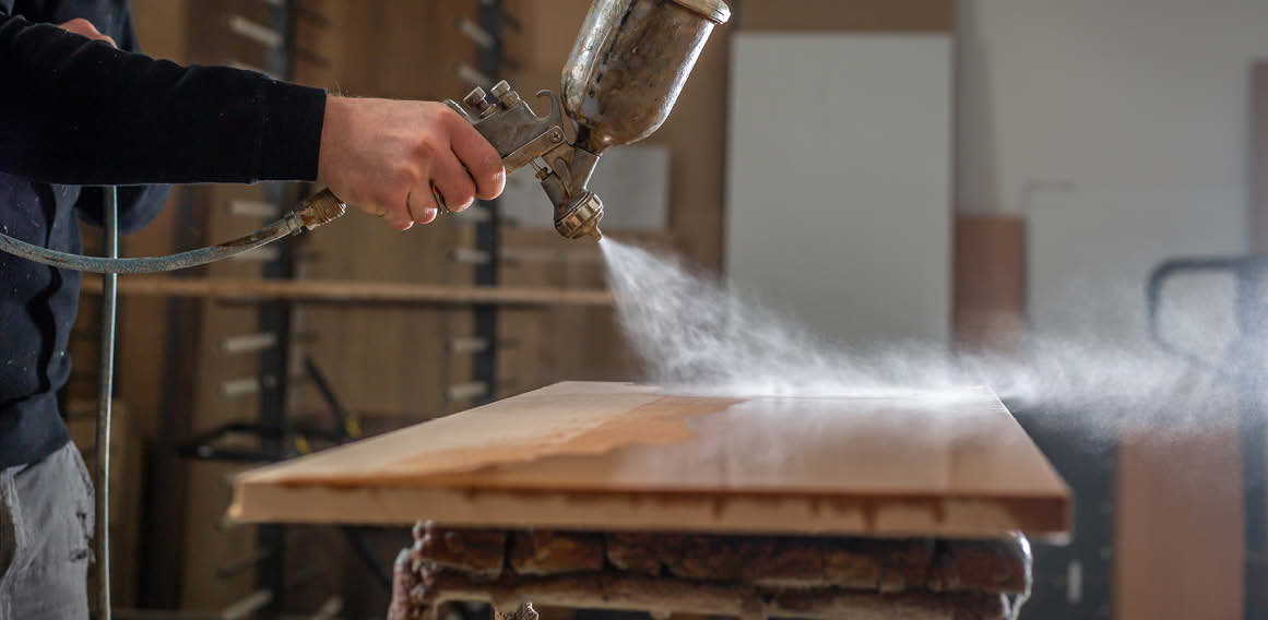 Operario trabajando un soporte de madera con aceites y barniz, un tipo de acabado ideal para tableros naturales.
