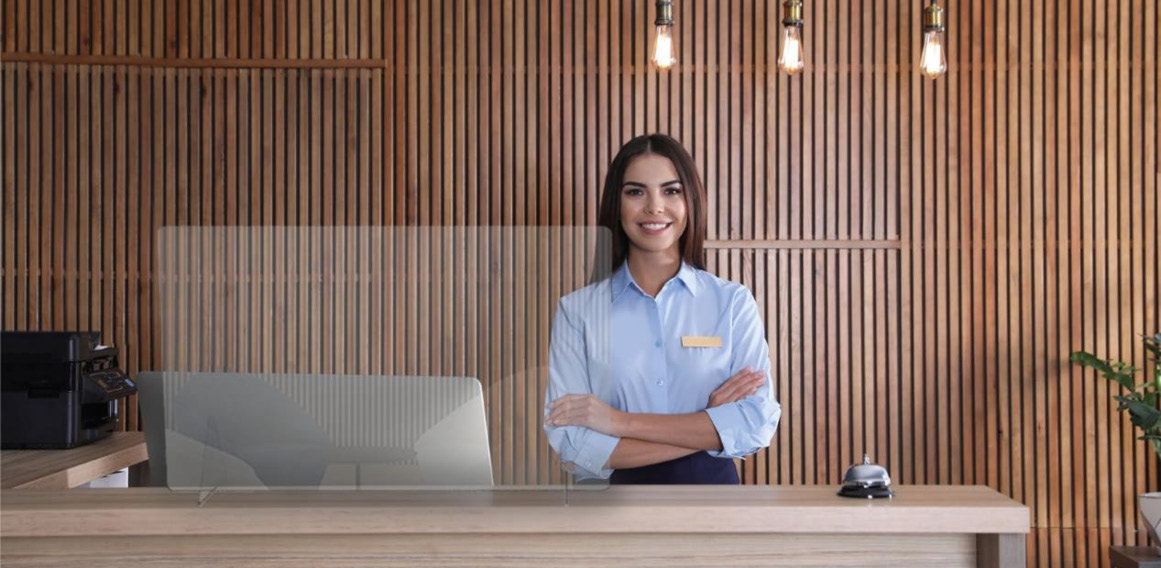 Recepcionista de hotel detrás de un separador de protección