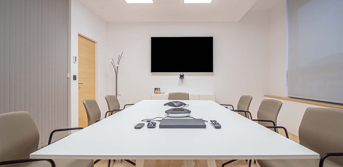 Sala de reuniones de equipo con pantalla y tecnología adaptada a oficina híbrida